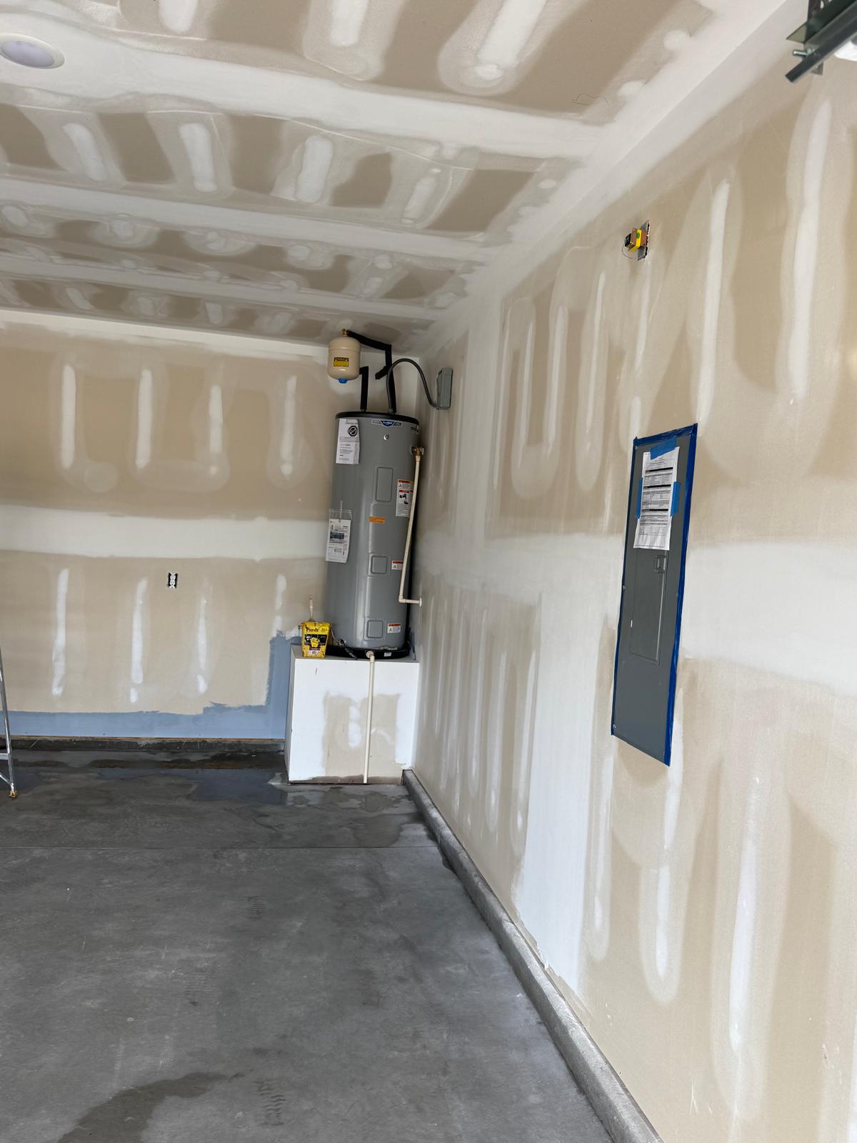 Unfinished garage with taped drywall and raw concrete